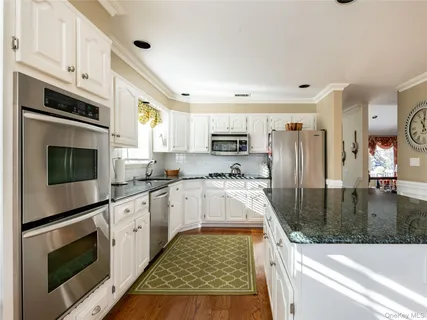 a kitchen with kitchen island granite countertop a stove sink and cabinets