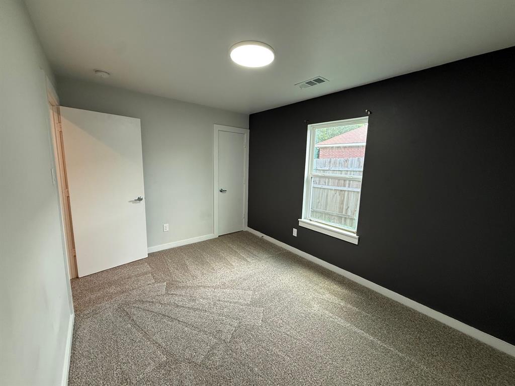 505 Thomas Street Terrell, TX 75160 - Photo 29 of 38 Carpeted interior room with light grey walls and a contrasting dark accent wall