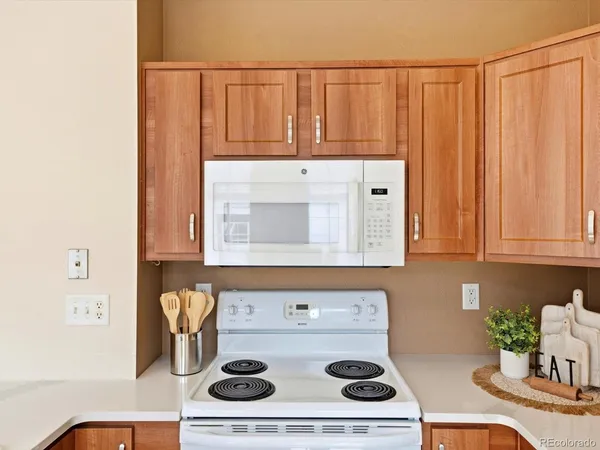 a kitchen with a sink stove and white cabinets with wooden floor