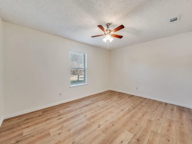 a view of an empty room with chandelier fan and wooden floor