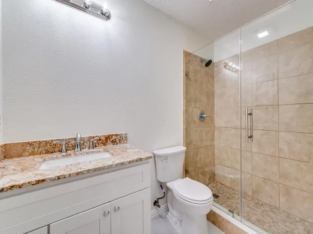 a bathroom with a granite countertop sink a toilet and a shower