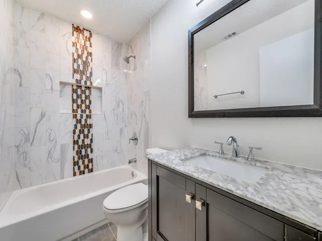 a bathroom with a granite countertop sink toilet mirror and shower