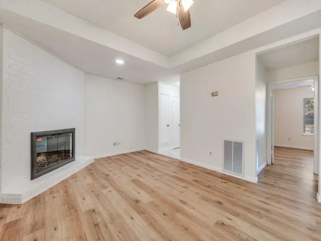 a view of an empty room with wooden floor fireplace and a window
