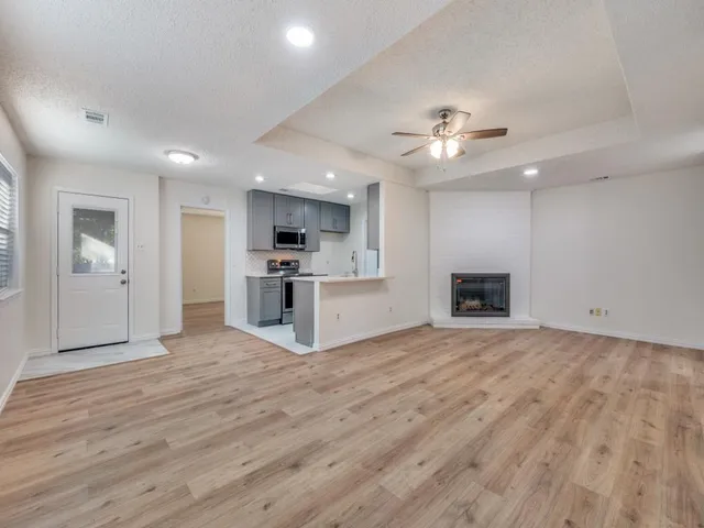 a view of empty room with wooden floor and kitchen view