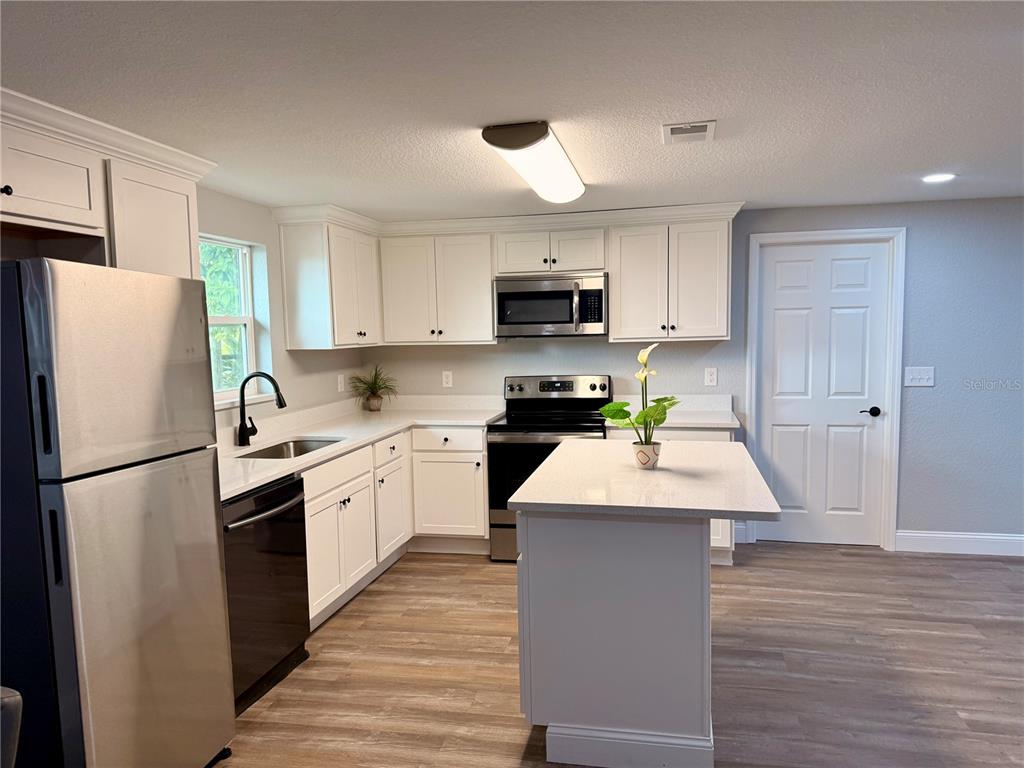 111 Water Tank Road Haines City, FL 33844 - Photo 6 of 48 a kitchen with kitchen island granite countertop a refrigerator stove top oven and sink
