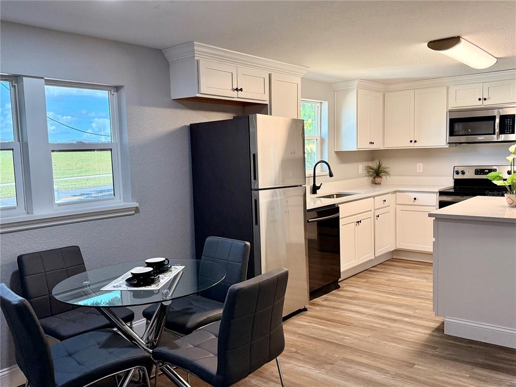 111 Water Tank Road Haines City, FL 33844 - Photo 7 of 48 a kitchen with stainless steel appliances kitchen island granite countertop a sink dishwasher a stove a refrigerator and a dining table with wooden cabinet