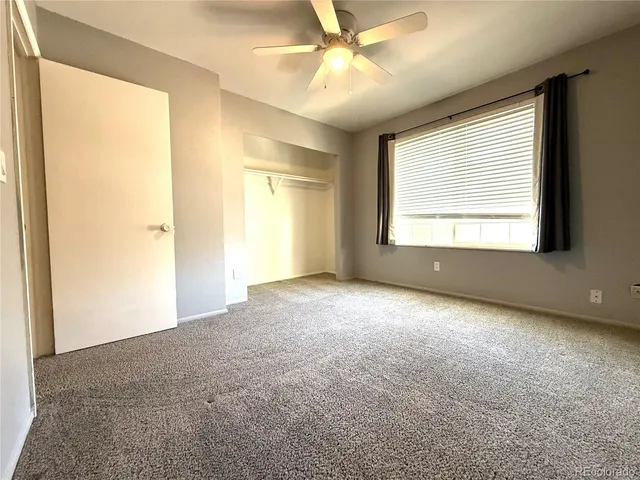 an empty room with a chandelier fan and windows