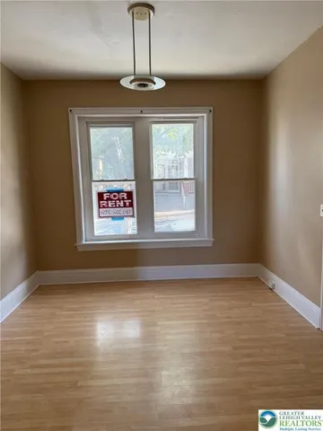 a view of an empty room with window and wooden floor