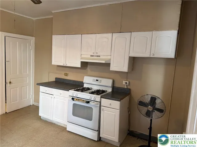 a kitchen with granite countertop white cabinets and white appliances