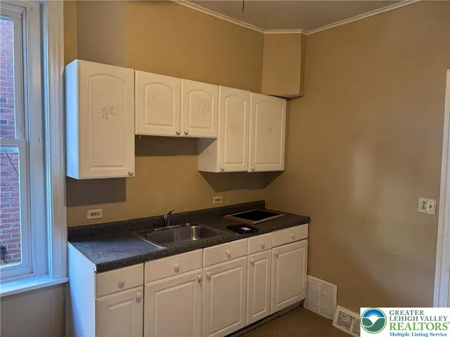 a kitchen with granite countertop a sink a stove and cabinets