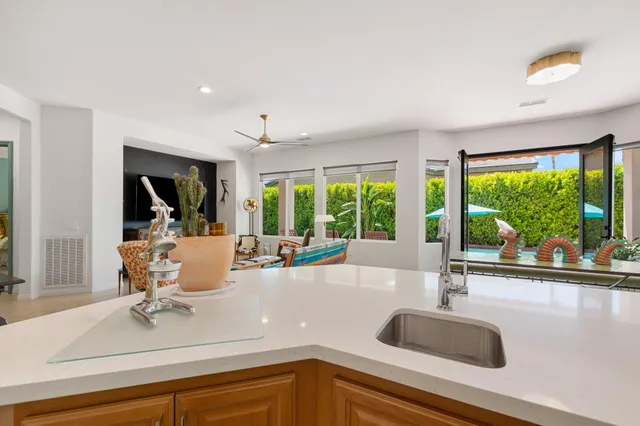 a view of a kitchen with kitchen island a large window cabinets a sink and stainless steel appliances