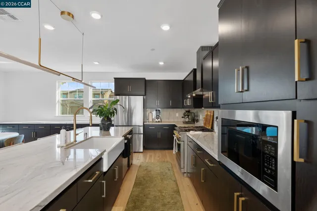 a kitchen with kitchen island granite countertop lots of counter top space a sink stainless steel appliances and cabinets