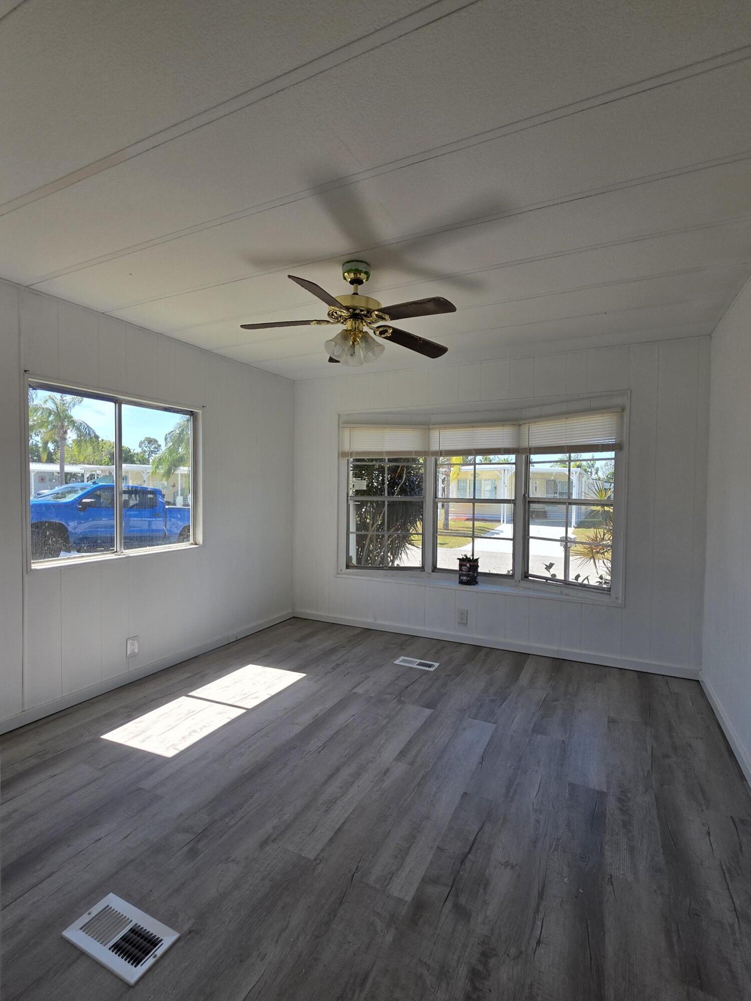 8 Del Sol Port St. Lucie, FL 34952 - Photo 20 of 26 an empty room with wooden floor fan and windows
