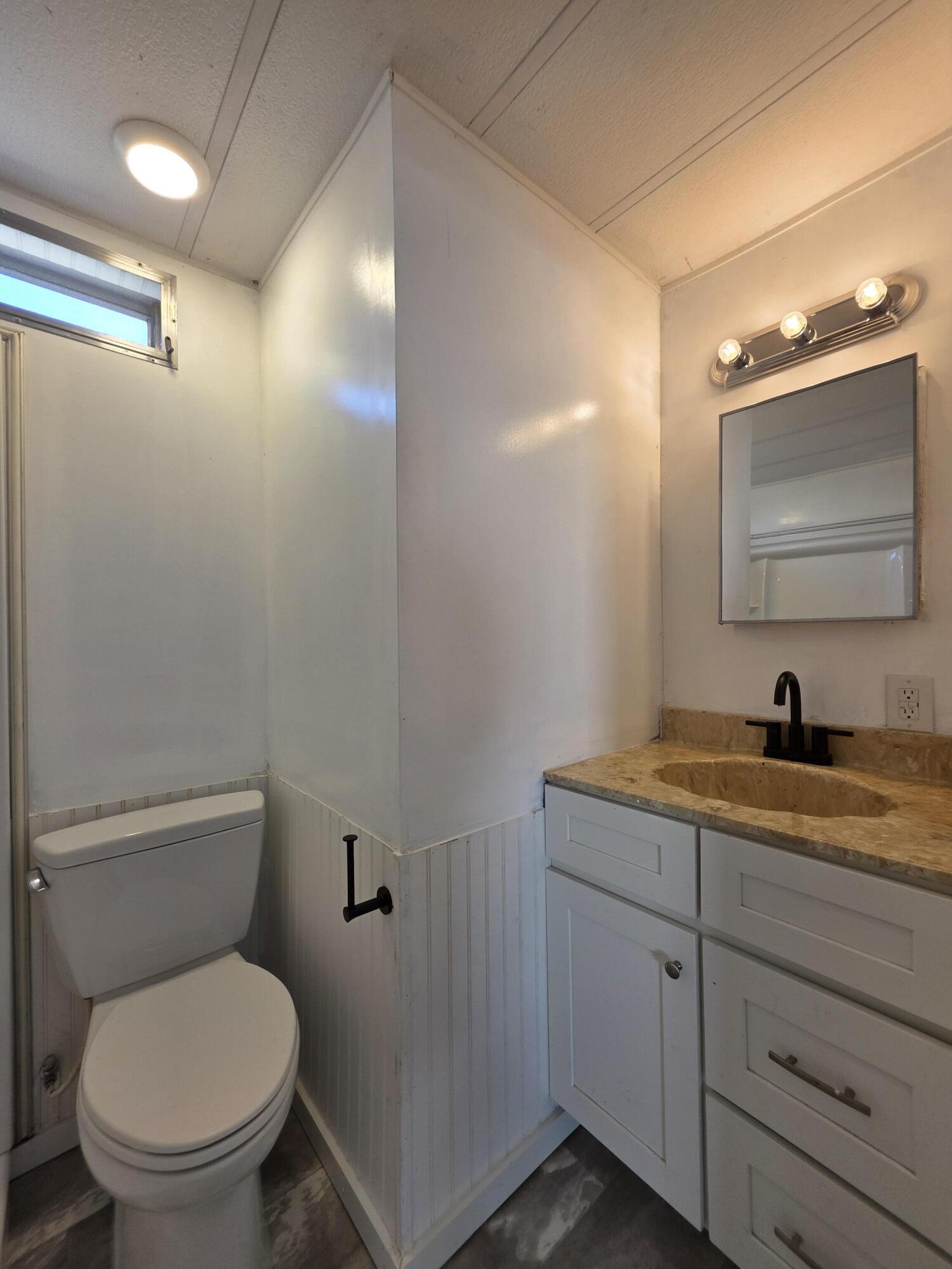 8 Del Sol Port St. Lucie, FL 34952 - Photo 24 of 26 a bathroom with a toilet sink vanity and mirror