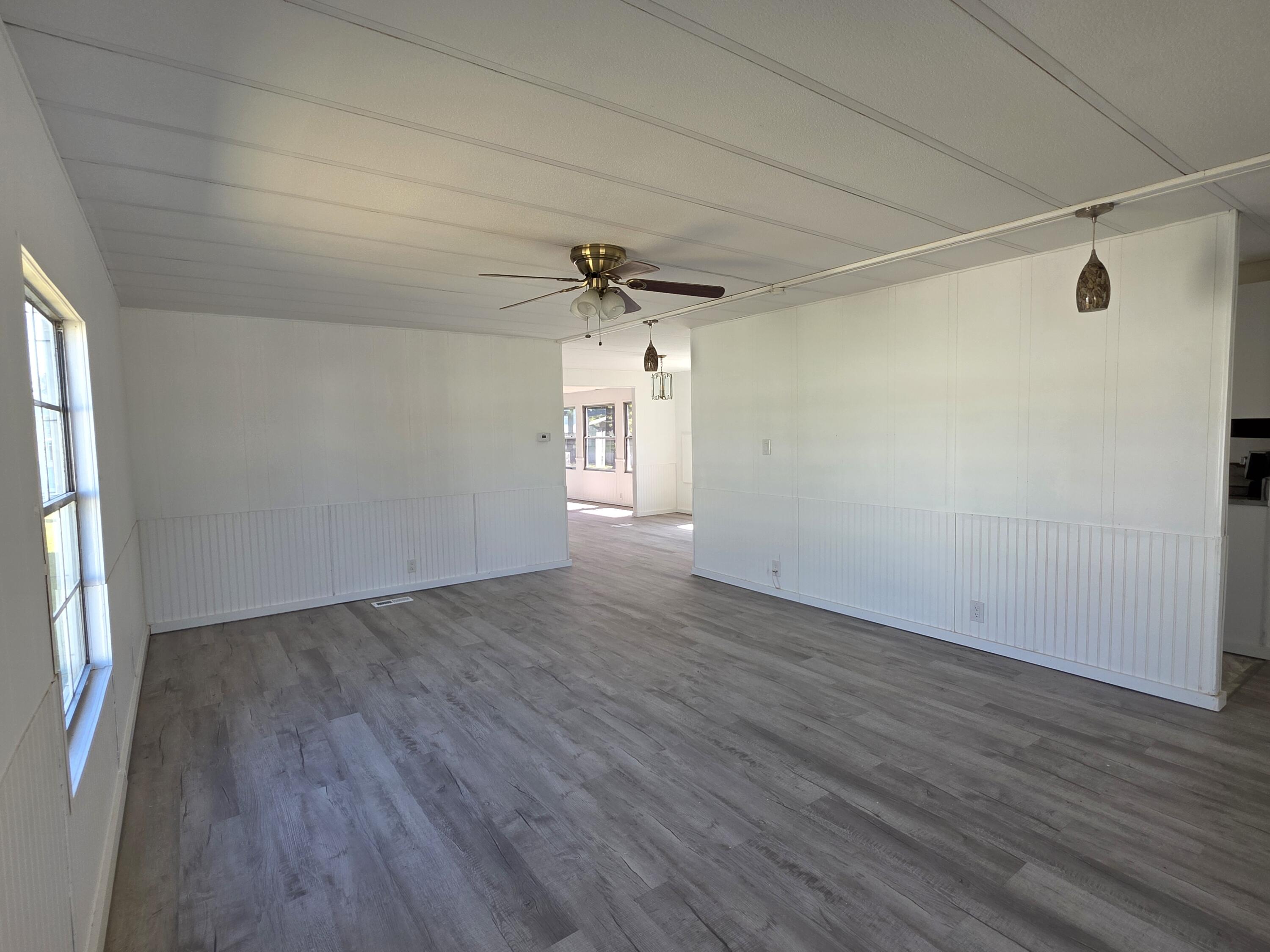 8 Del Sol Port St. Lucie, FL 34952 - Photo 5 of 26 an empty room with wooden floor fan and windows