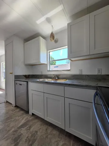 a kitchen with granite countertop white cabinets and a sink