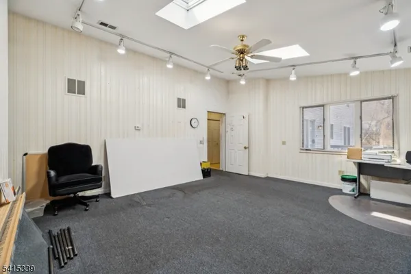 an empty room with windows and ceiling fan