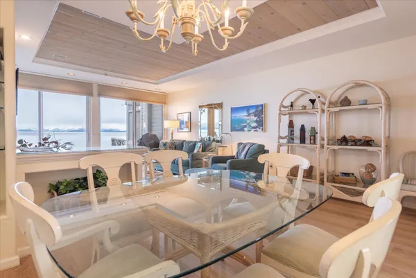 a view of a dining room with furniture a chandelier and large windows