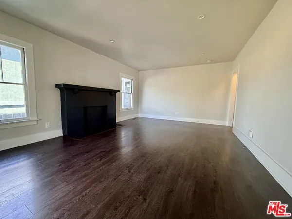an empty room with wooden floor fireplace and windows