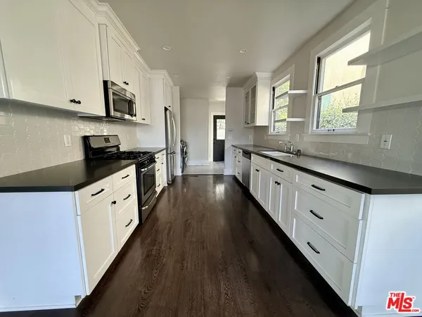 a large kitchen with stainless steel appliances kitchen island granite countertop white cabinets a sink and a stove