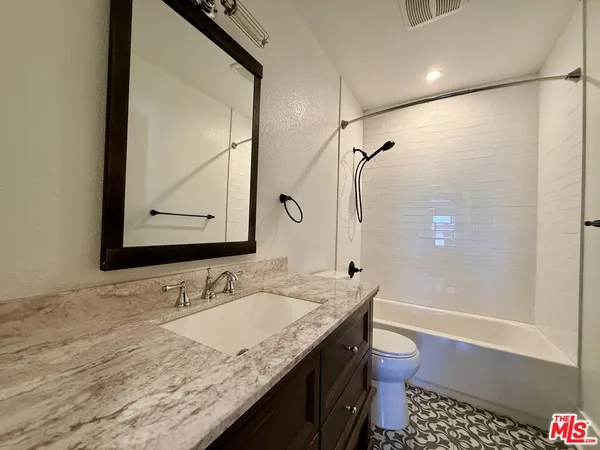 a bathroom with a granite countertop sink a toilet and shower