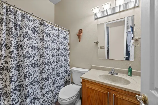 a bathroom with a granite countertop toilet sink mirror and shower