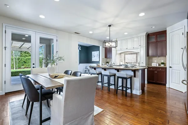 a kitchen with stainless steel appliances kitchen island granite countertop a table chairs stove and refrigerator