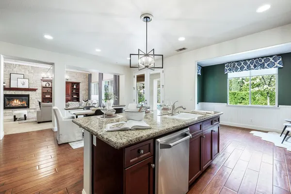 a kitchen with stainless steel appliances kitchen island granite countertop a table chairs and a refrigerator