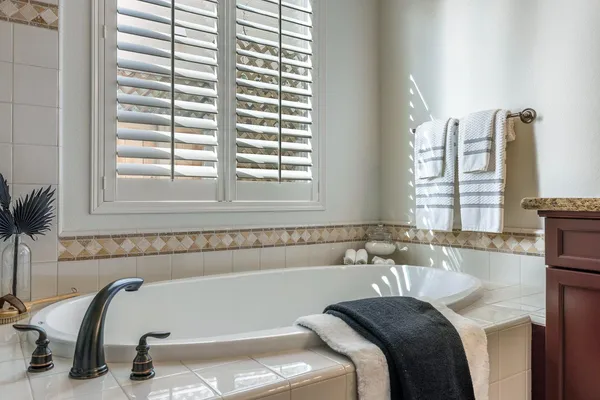 a spacious bathroom with a granite countertop sink a large mirror a bathtub and window