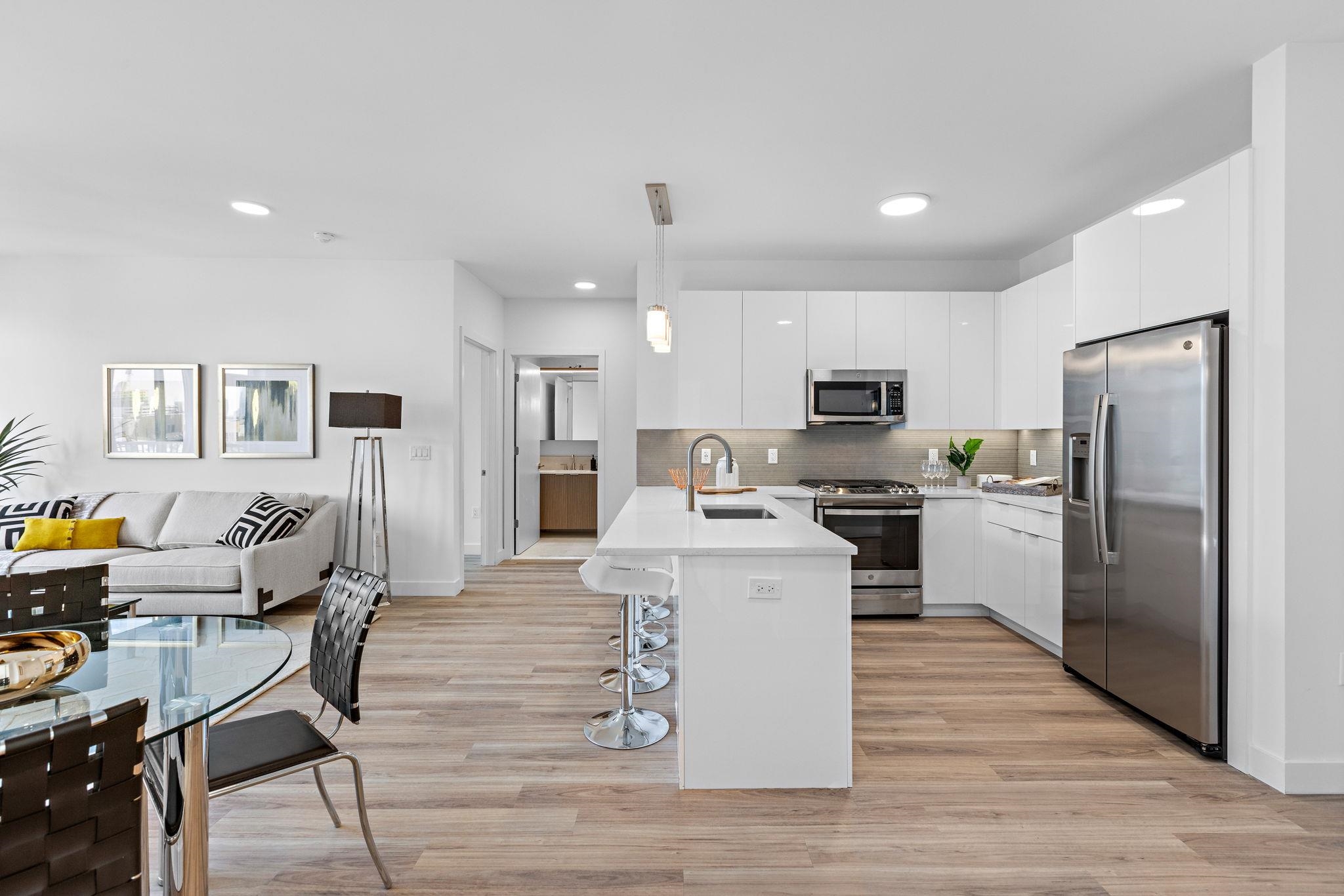 5711 John F. Kennedy Boulevard, Unit 306 North Bergen, NJ 07047 - Photo 5 of 31 a kitchen with stainless steel appliances kitchen island granite countertop a refrigerator a stove top oven a sink dishwasher a dining table and chairs with wooden floor