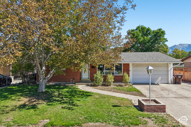 7391 Ramanee Drive Midvale, UT 84047 - Photo 39 of 45 Brick exterior with an attached two-car garage, mature front yard tree, and concrete walkway