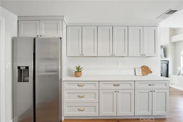 a kitchen with white cabinets and refrigerator