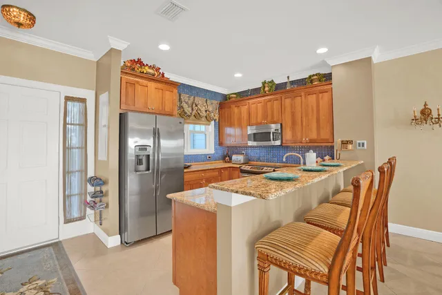 a kitchen with stainless steel appliances granite countertop a refrigerator a stove a sink a dining table and chairs