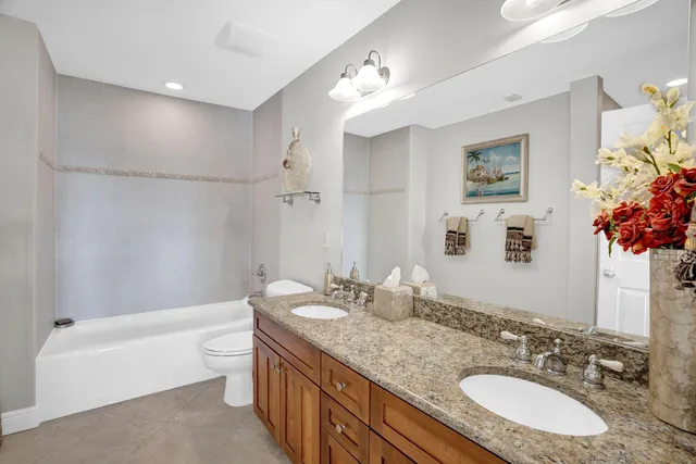 a bathroom with a granite countertop sink a toilet a mirror a vanity a bathtub and shower