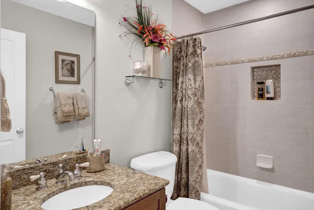 a bathroom with a granite countertop sink a toilet and shower