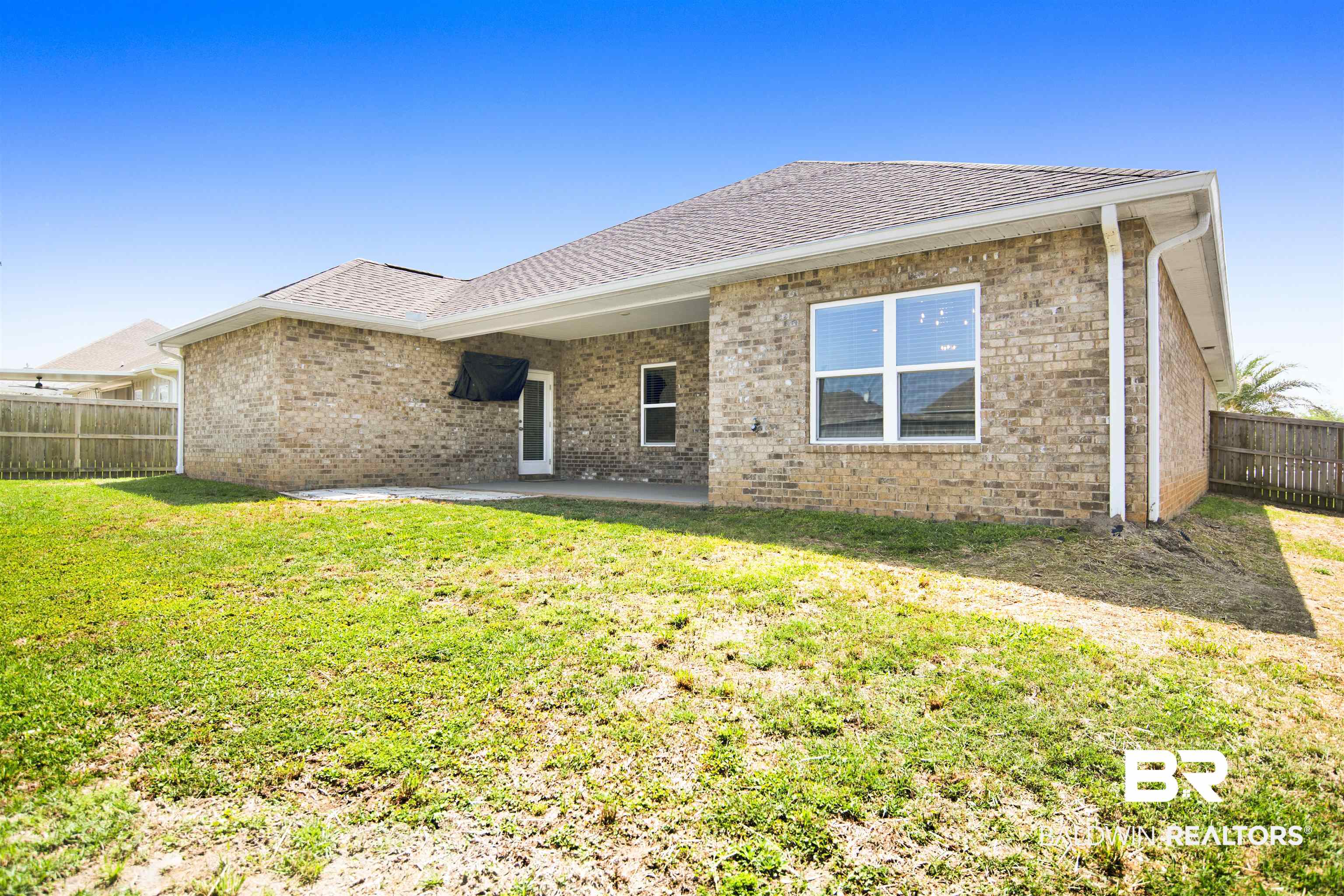8493 Bronze Lane Foley, AL 36535 - Photo 32 of 38 Expansive rear yard featuring a brick exterior with a covered patio, multiple windows, and a wood privacy fence