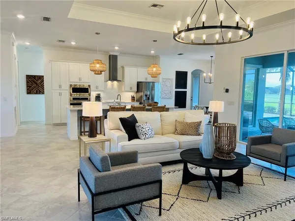 a living room with furniture kitchen view and a chandelier