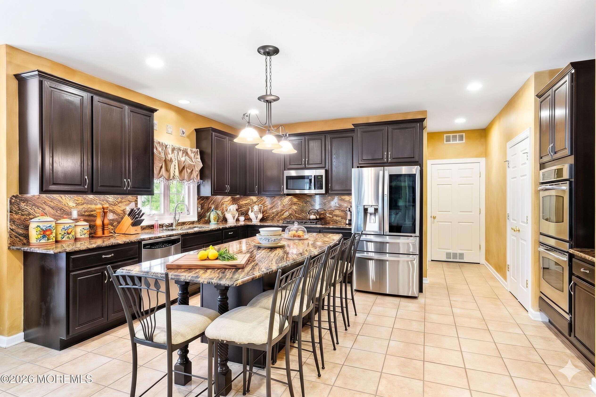 2 Mehar Court Jackson, NJ 08527 - Photo 11 of 47 a kitchen with stainless steel appliances kitchen island granite countertop a refrigerator a stove a sink a dining table and chairs with wooden floor