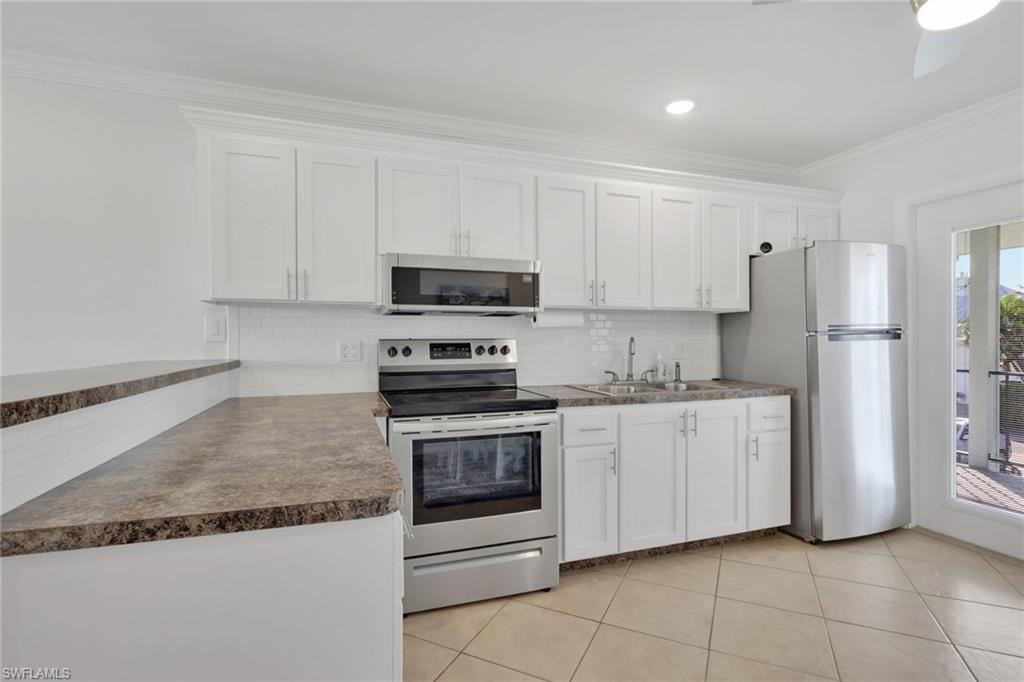 466 12th Avenue South, Unit 466 Naples, FL 34102 - Photo 13 of 34 a kitchen with stainless steel appliances granite countertop a refrigerator sink and white cabinets
