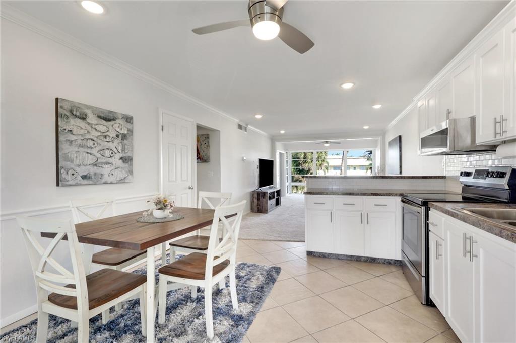 466 12th Avenue South, Unit 466 Naples, FL 34102 - Photo 16 of 34 a kitchen with stainless steel appliances kitchen island granite countertop a stove a sink a dining table and chairs with wooden floor