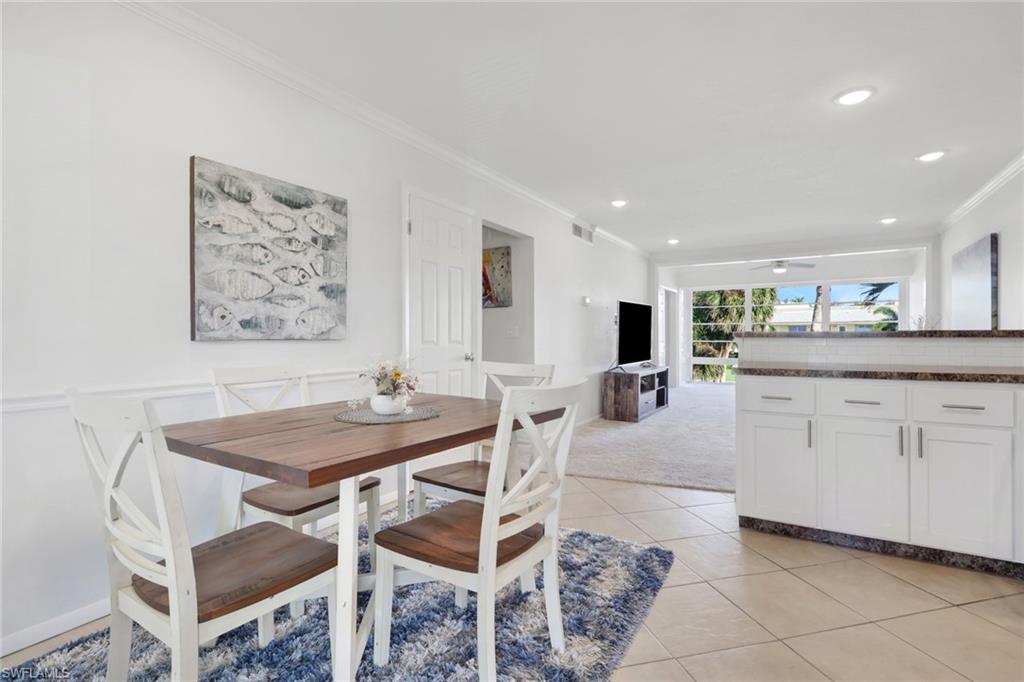 466 12th Avenue South, Unit 466 Naples, FL 34102 - Photo 10 of 34 a kitchen with a dining table chairs and white cabinets
