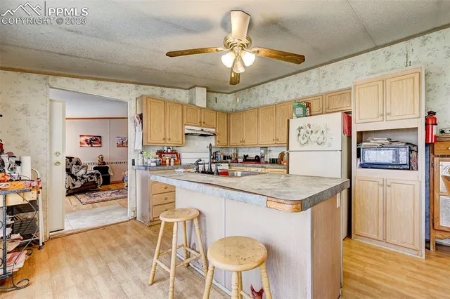 a kitchen with stainless steel appliances granite countertop a sink dishwasher and a refrigerator with wooden floor