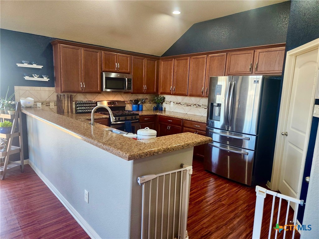 91 Skyview Terrace Leander, TX 78641 - Photo 14 of 25 a kitchen with stainless steel appliances granite countertop a refrigerator a stove a sink a microwave and wooden floors