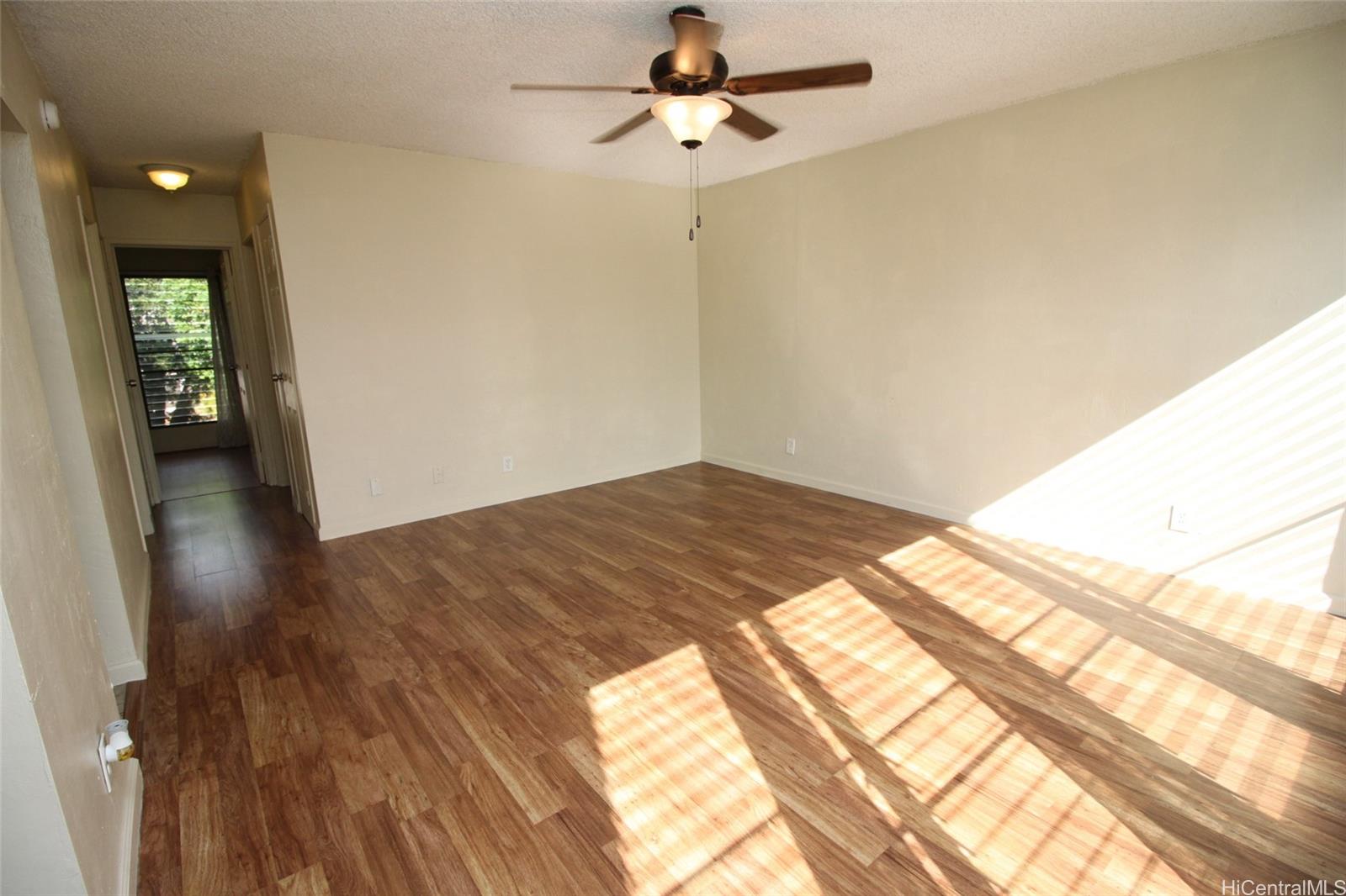 87-126 Helelua Street, Unit D204 Waianae, HI 96792 - Photo 6 of 13 a view of a hallway with wooden floor and a chandelier fan