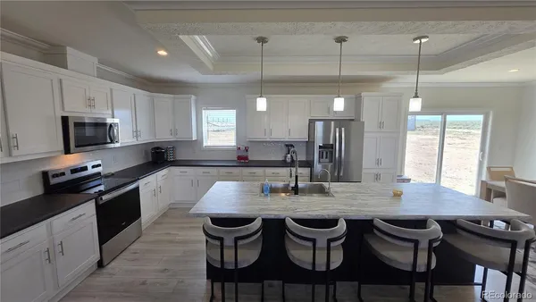 a kitchen with stainless steel appliances granite countertop a stove top oven a sink a dining table and chairs