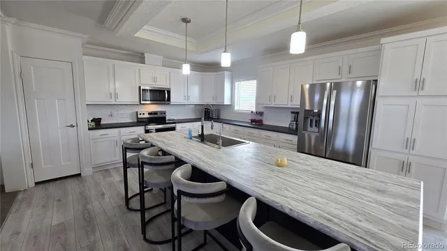 a kitchen with stainless steel appliances granite countertop a table chairs refrigerator and microwave