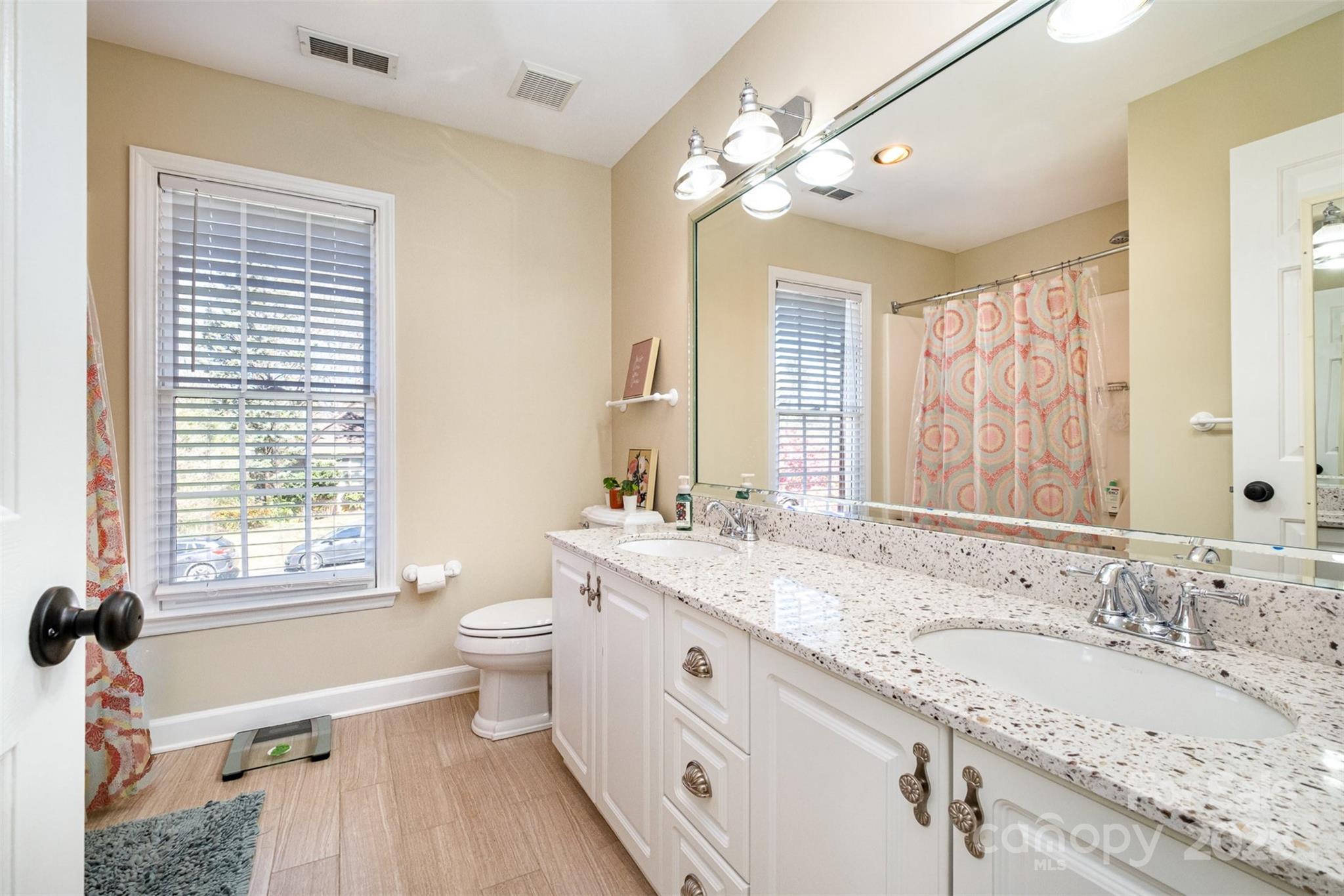 11122 Windgate Court Tega Cay, SC 29708 - Photo 23 of 48 a spacious bathroom with a granite countertop double vanity sink a mirror and a bathtub