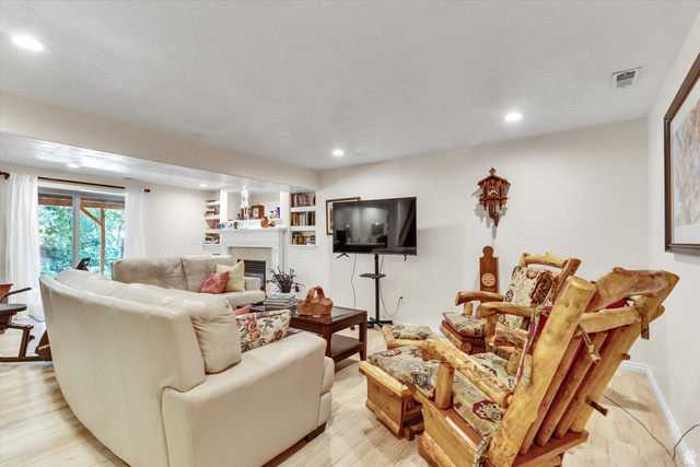 2863 Fallentine Road Sandy, UT 84093 - Photo 35 of 48 Recreation room featuring recessed lighting, light wood-finish flooring, a built-in fireplace with mantel, and integrated shelving
