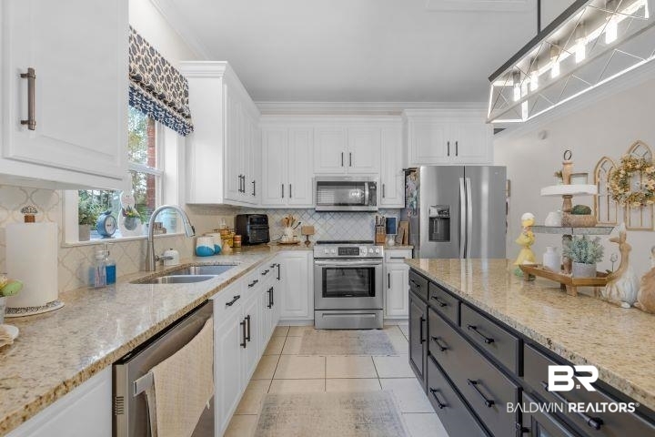 24541 Baldwin Beach Expressway Robertsdale, AL 36567 - Photo 11 of 51 Kitchen featuring white cabinetry, light stone countertops, a sink, and stainless steel appliances
