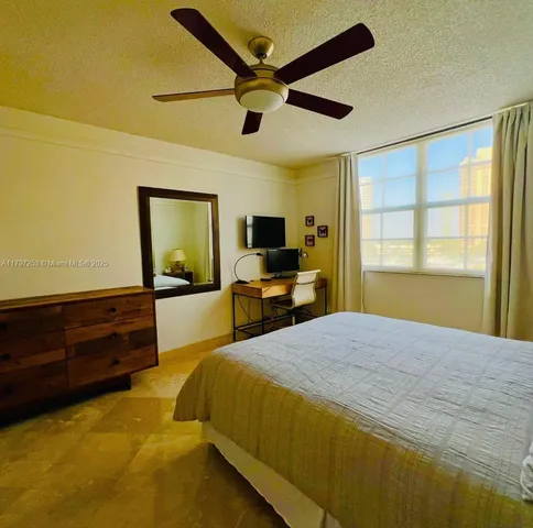 a bedroom with a bed a window and a flat screen tv